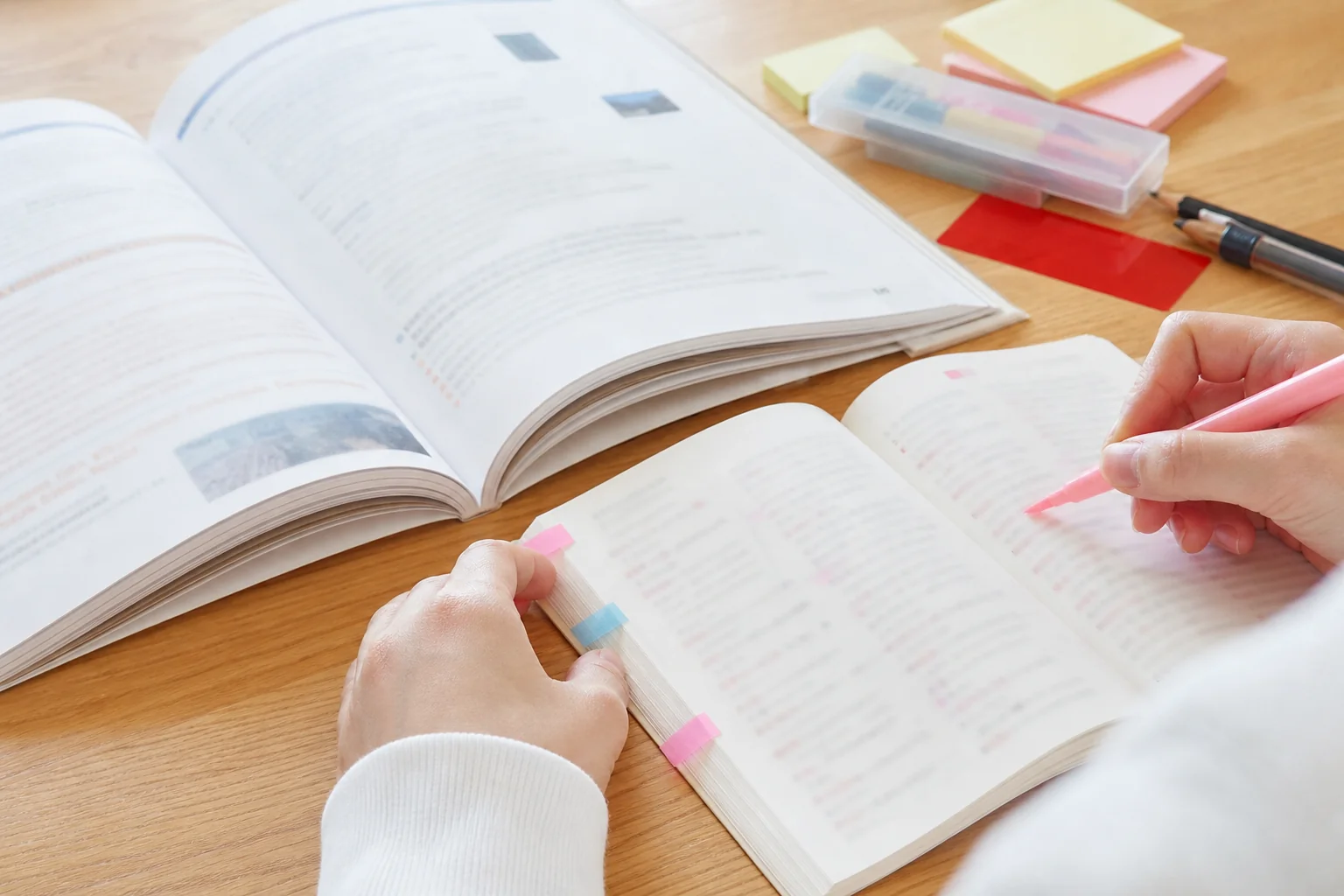 教科書と中学生向けの熟語集を並べ、教科書で習った英熟語に印をつけている中学生の手元の写真